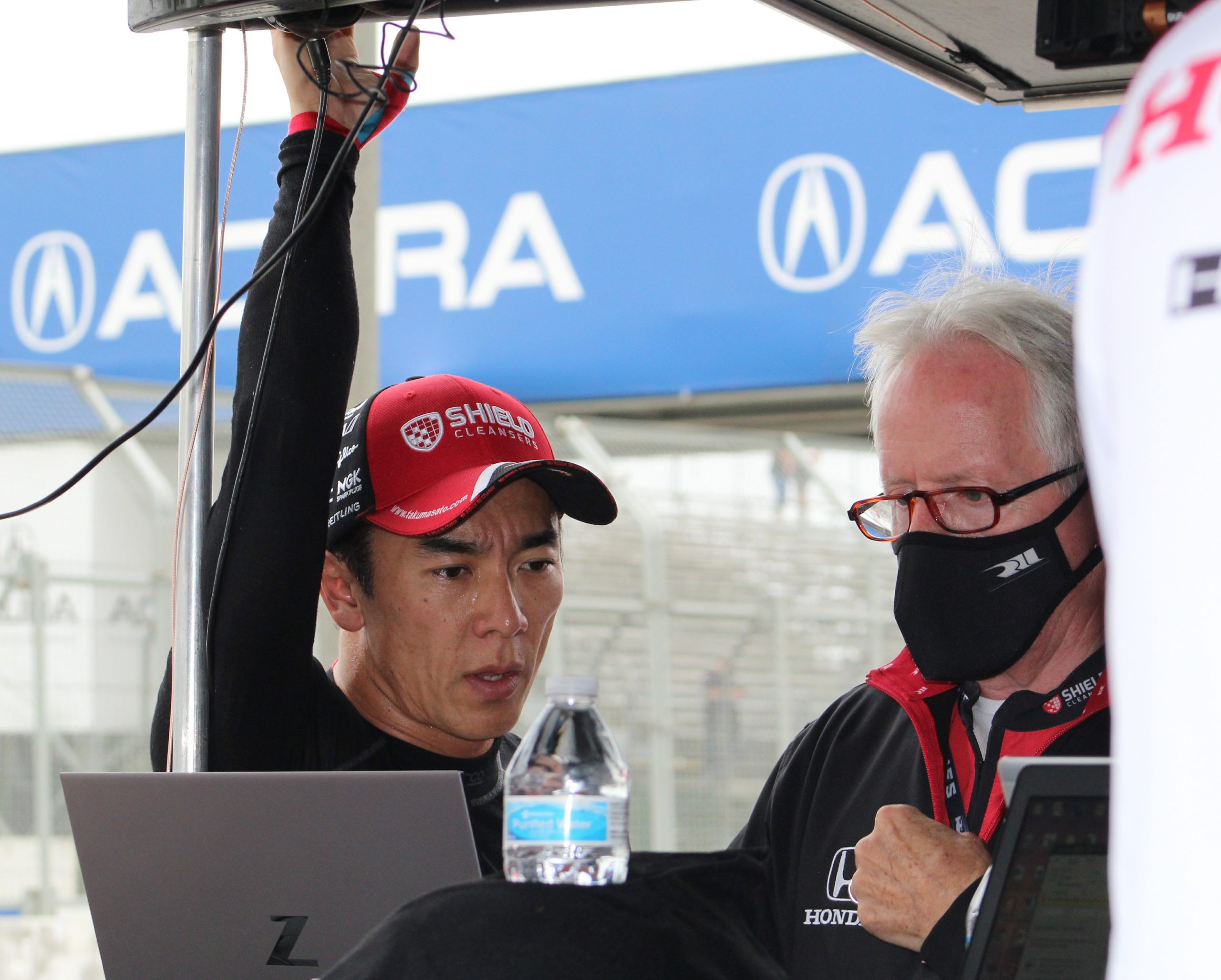 Takuma Sato looks at data with his crew to figure out how to go faster after the Sunday morning warm-up.