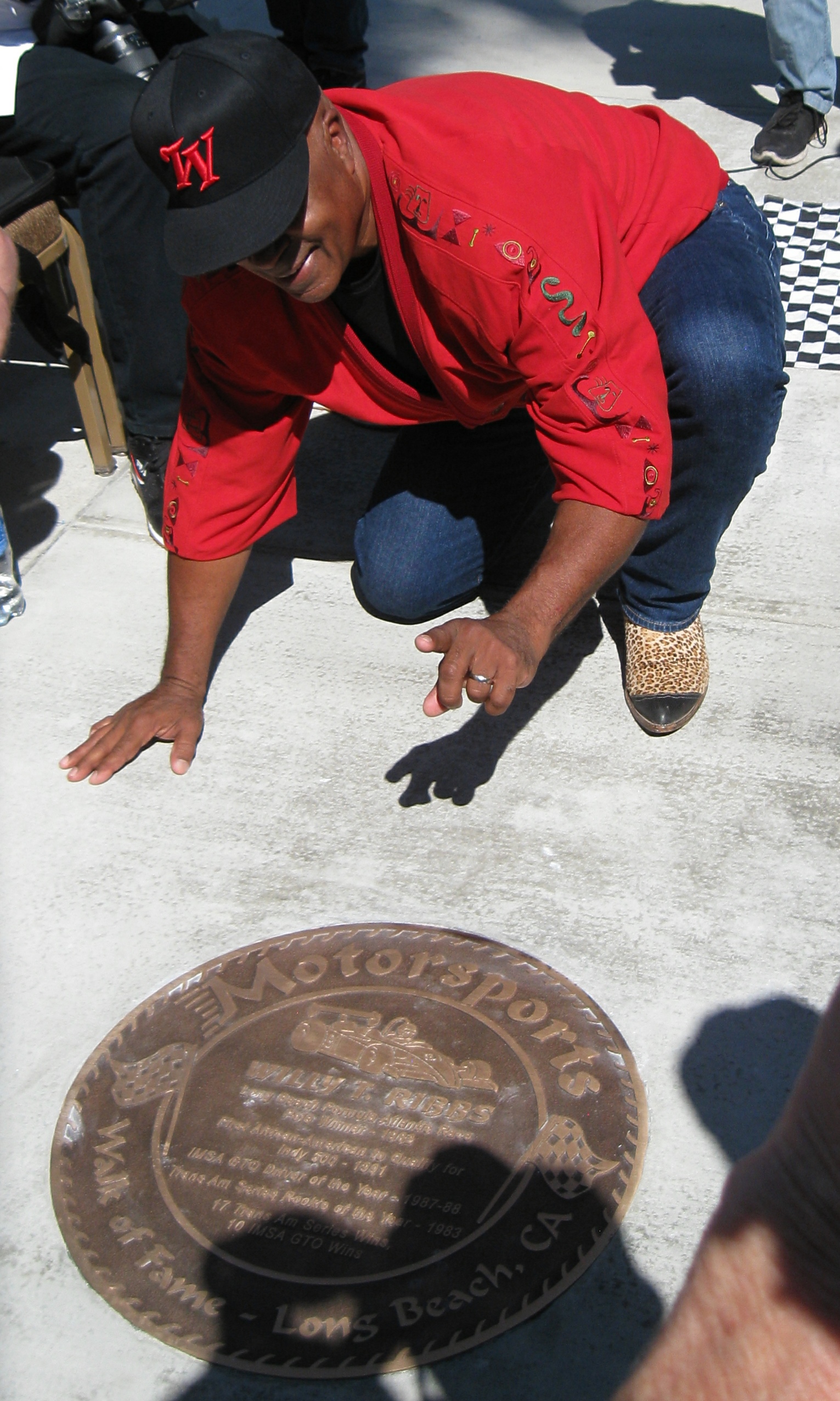 Willy T holds up a number one sign right before he kisses the plaque as if he were kissing the bricks at the Indianapolis Motor Speedway.